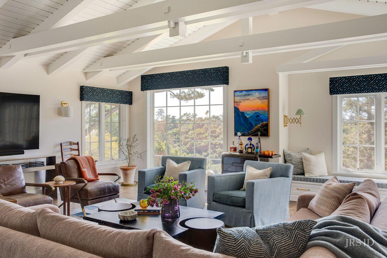 Montecito living room with vaulted ceilings, custom window seats, forest views, and layered California interior furnishings
