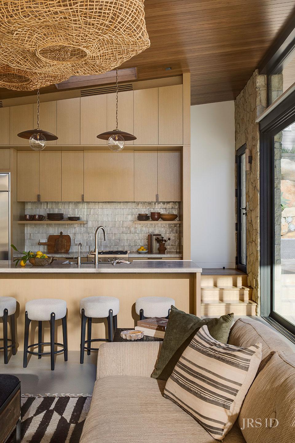 Custom kitchen with light oak cabinetry, stone backsplash, and waterfall island at the Eucalyptus Hill ADU Residence in Montecito.