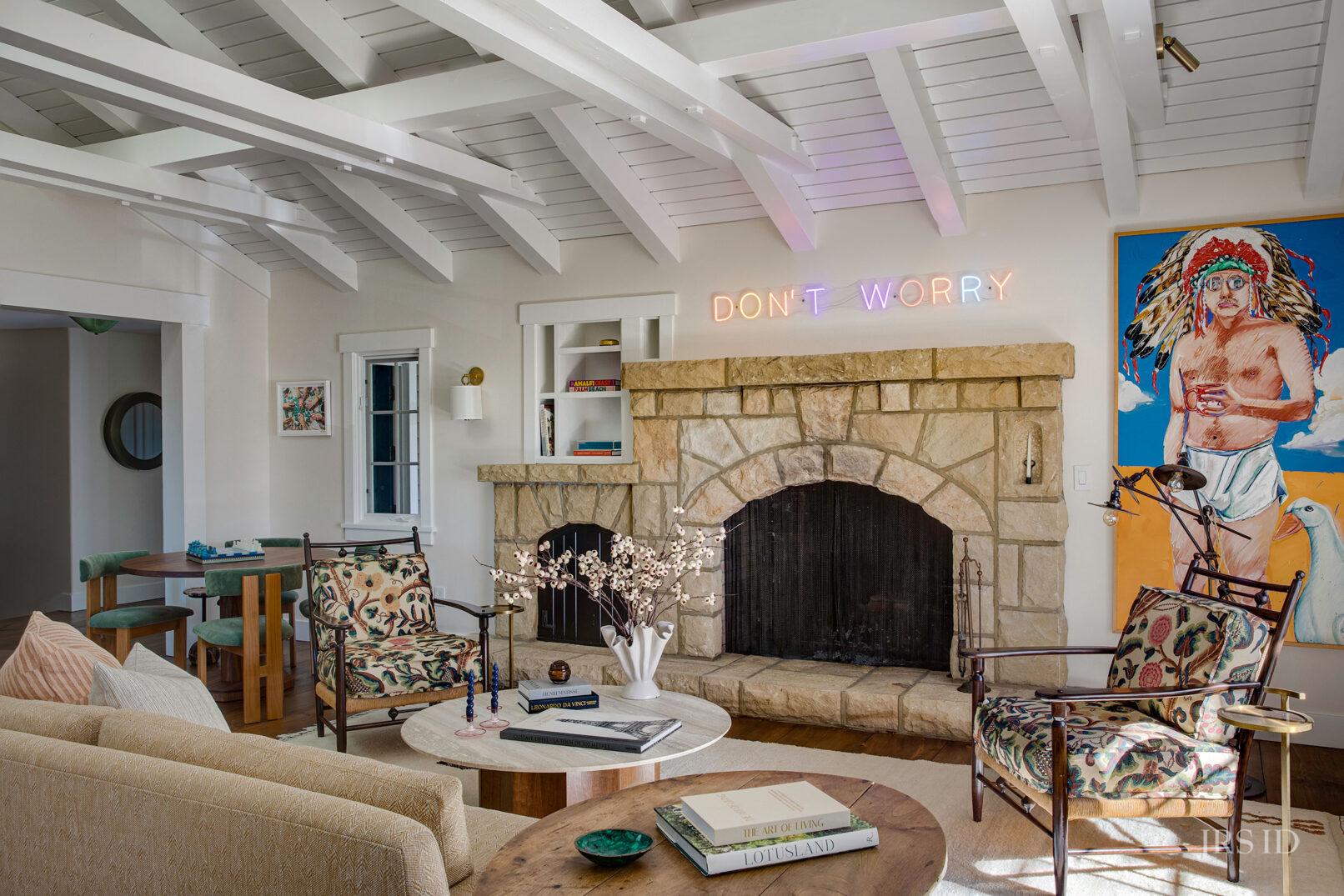 Stone fireplace in Montecito living room featuring curated furnishings, colorful artwork, and relaxed California interior design