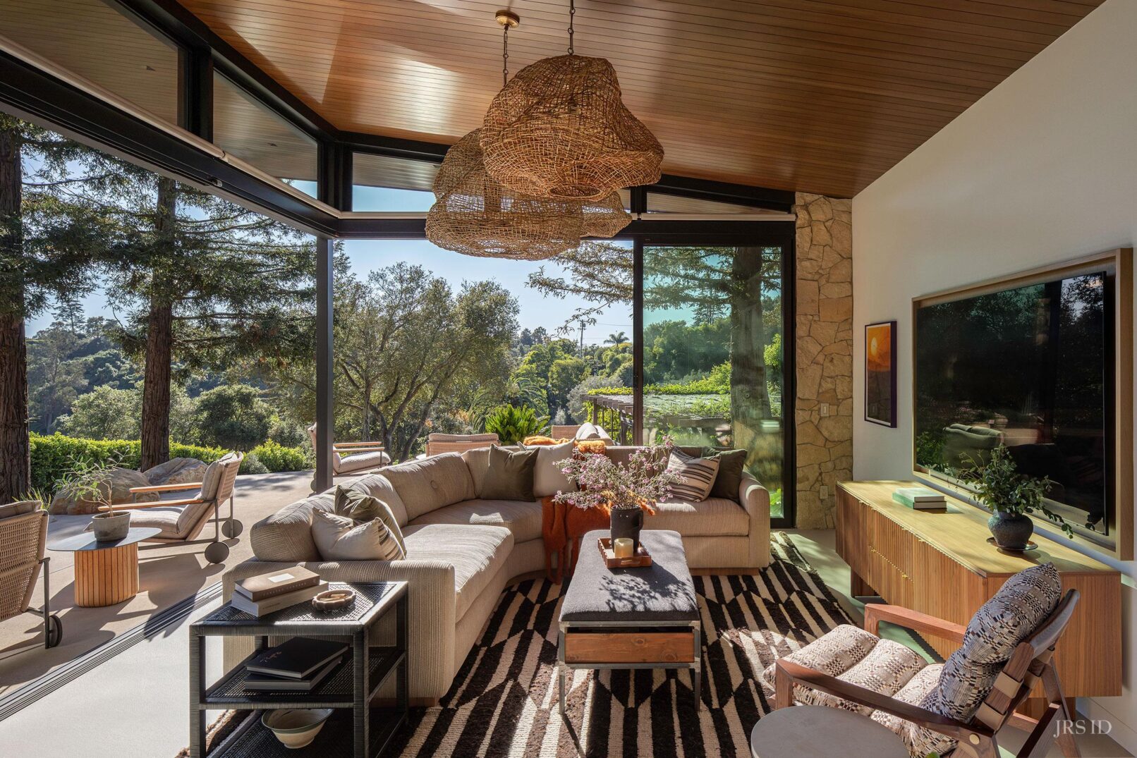Panoramic view of the living room with floor-to-ceiling glass doors opening to the landscape at the Eucalyptus Hill ADU Residence in Montecito.