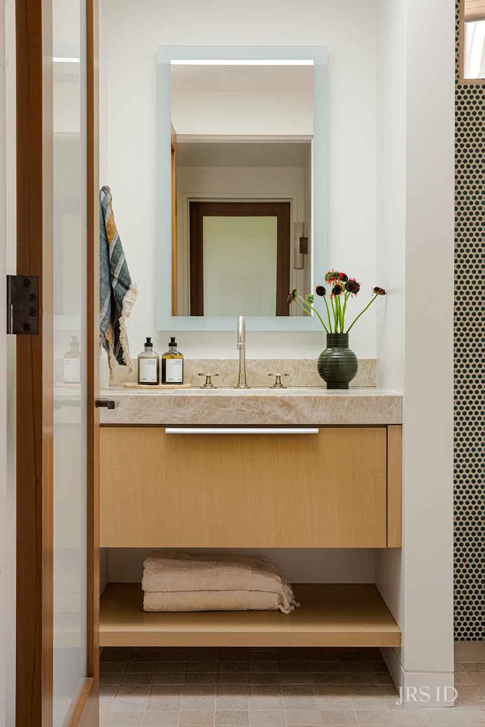 Custom bathroom vanity with stone countertop and light oak cabinetry at the Eucalyptus Hill ADU Residence in Montecito.