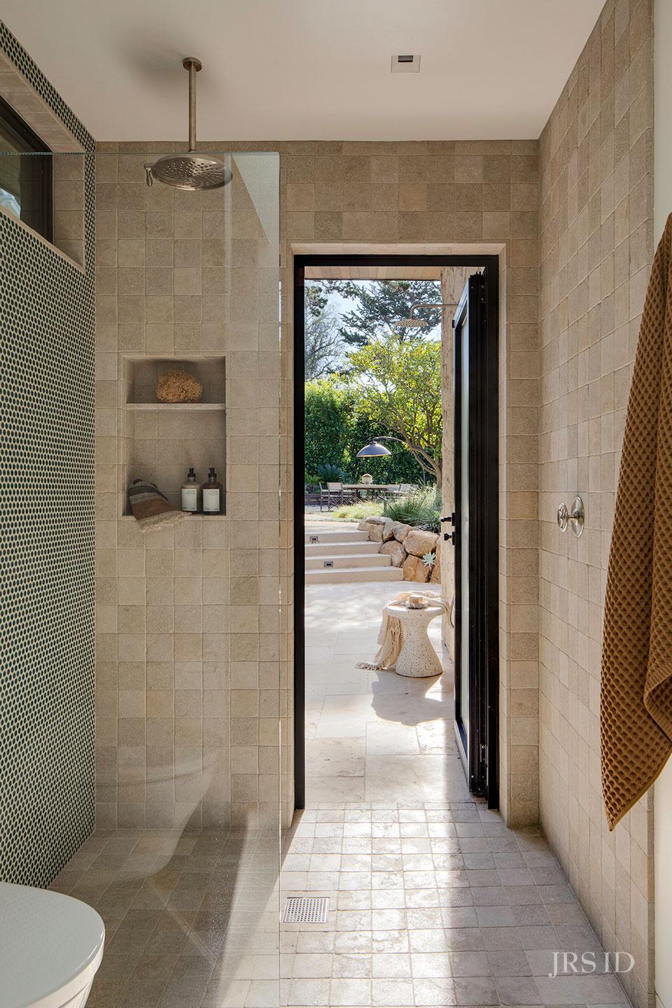 Walk-in shower with textured tile and direct access to a private outdoor courtyard at the Eucalyptus Hill ADU Residence in Montecito.