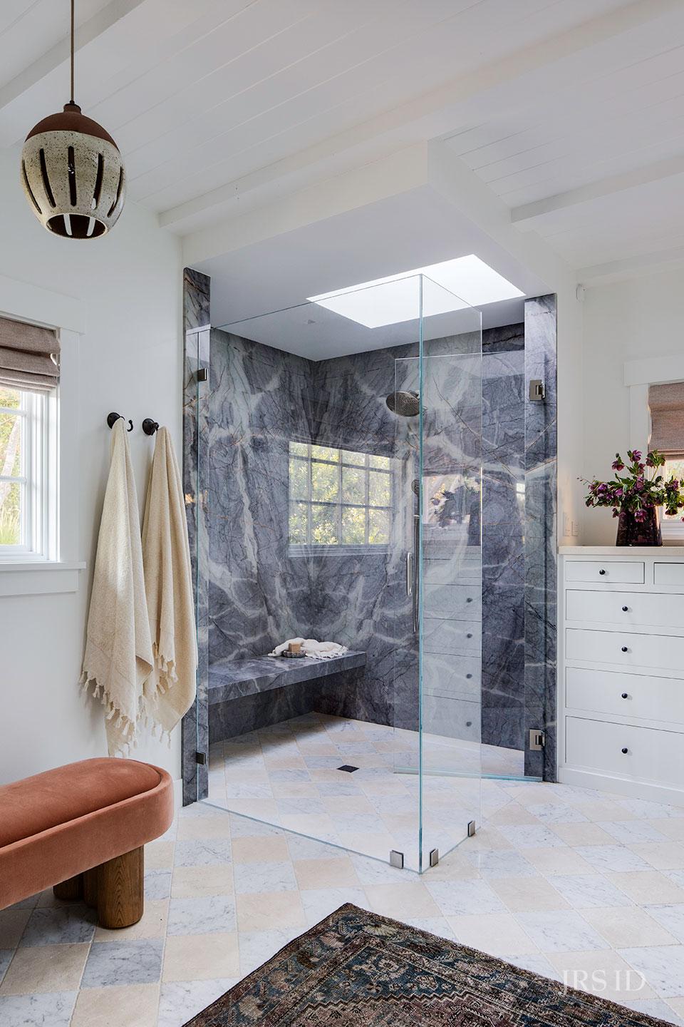 Luxury Montecito bathroom with dramatic stone slab shower, skylight, and custom California coastal interior design