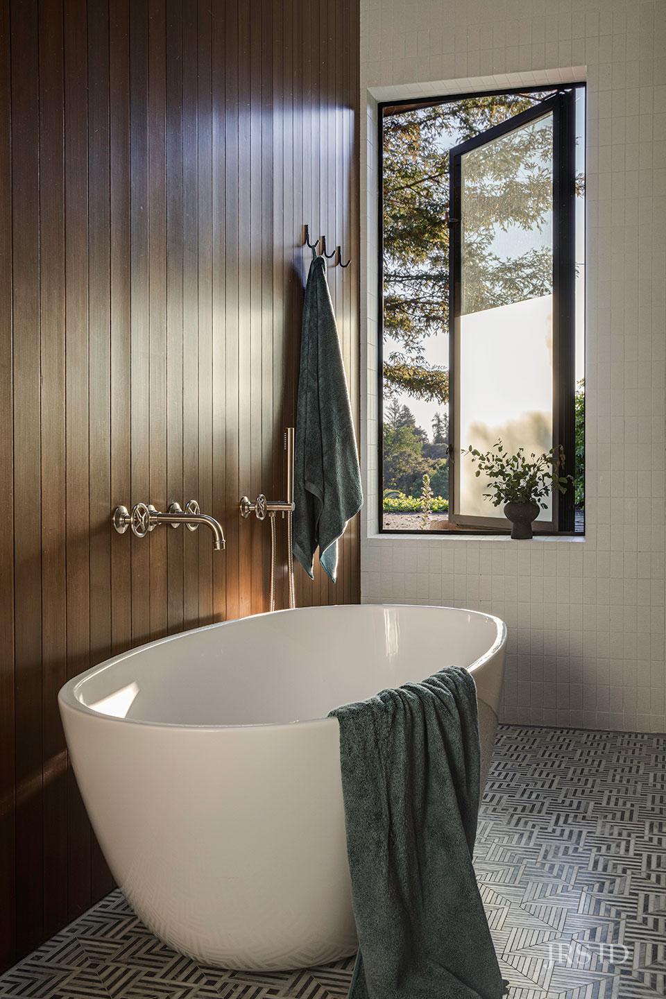Spa-inspired bathroom with freestanding soaking tub and wood-paneled accent wall at the Eucalyptus Hill ADU Residence in Montecito.