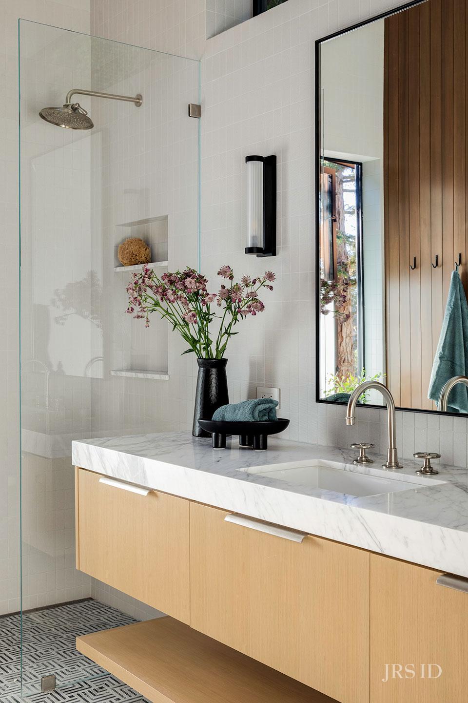 Bathroom with marble vanity, walk-in shower, and custom oak cabinetry at the Eucalyptus Hill ADU Residence in Montecito.